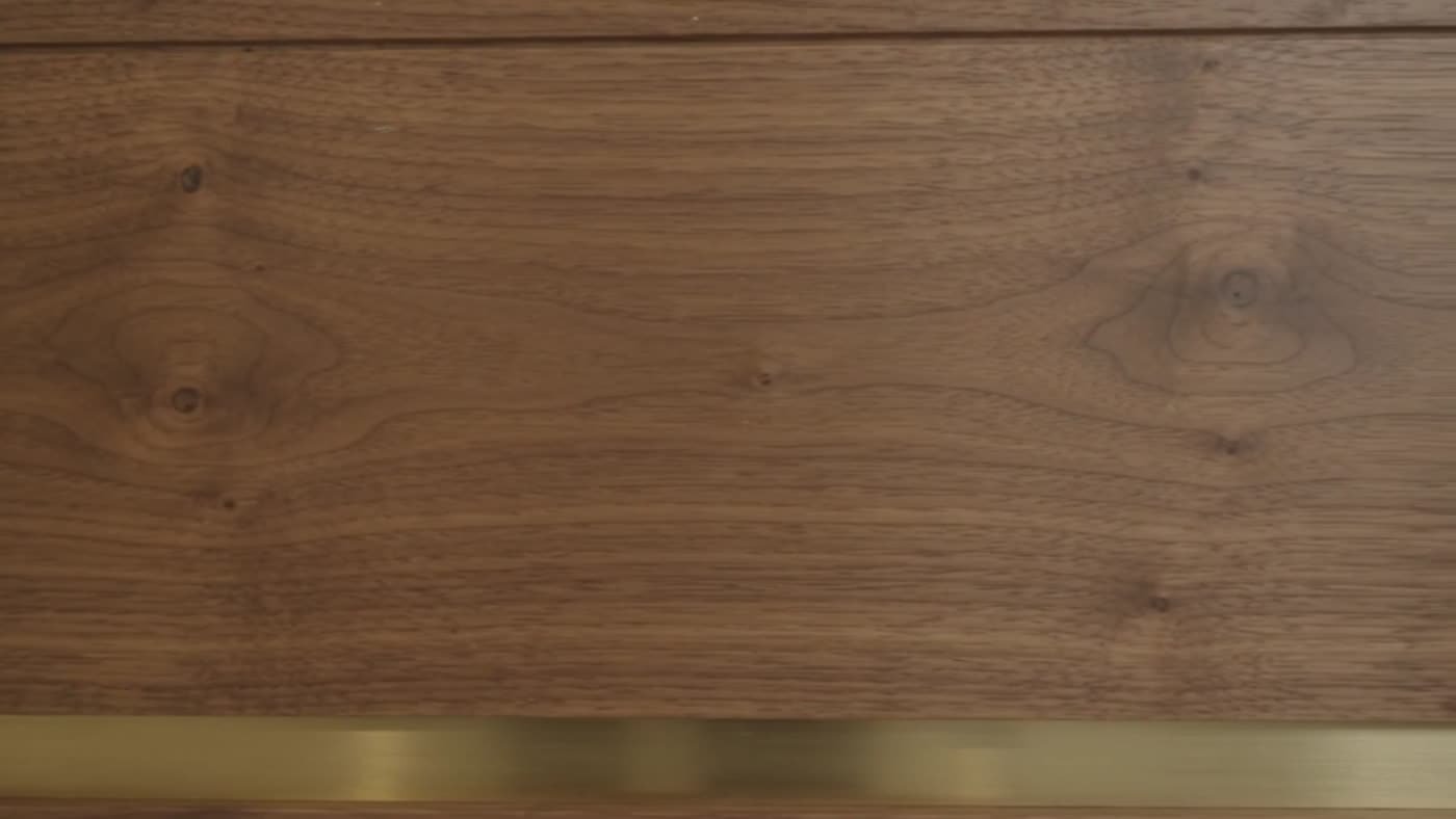 Close-up of walnut panel with brushed brass reveal